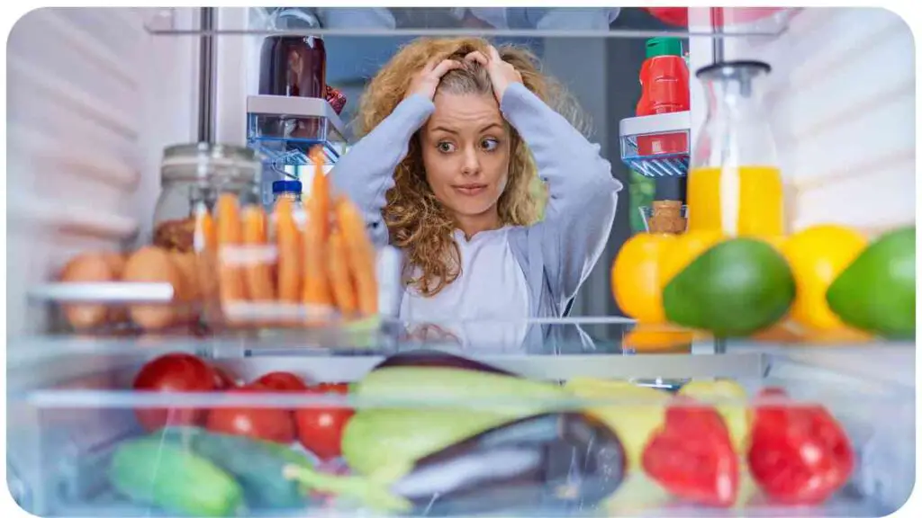 a person is standing in front of an open refrigerator full of fruit and vegetables