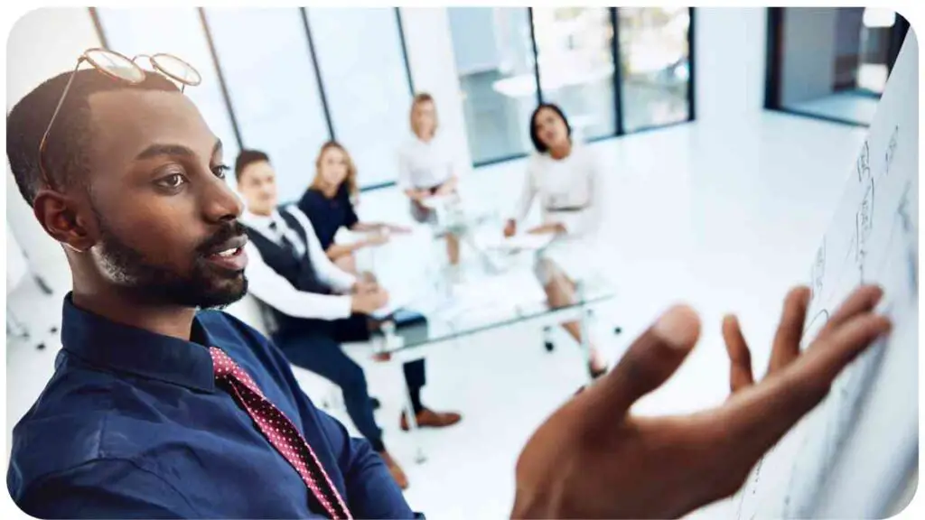 an individual pointing to a whiteboard in front of a group of business people