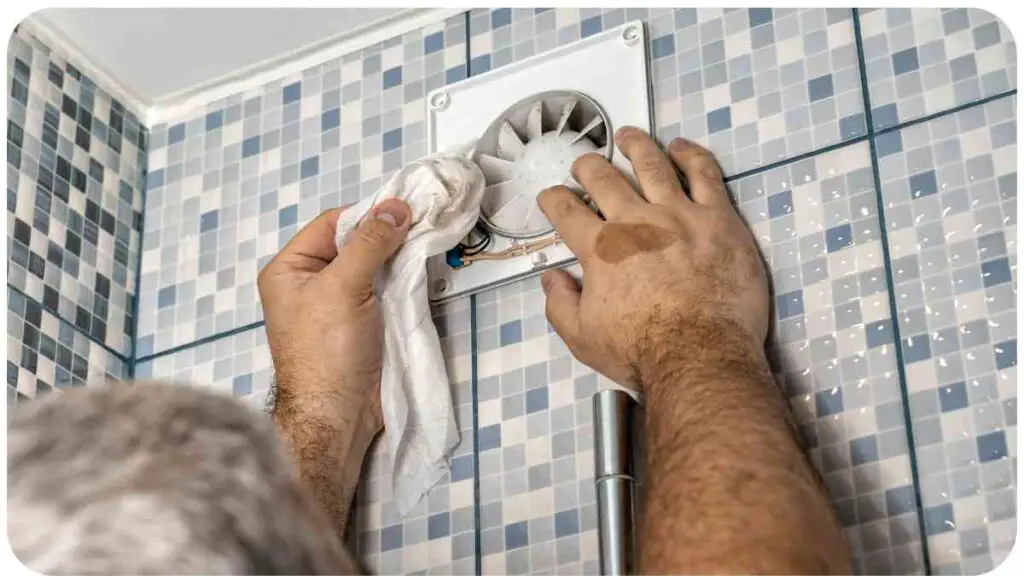 a person is fixing a shower fan in a tiled bathroom