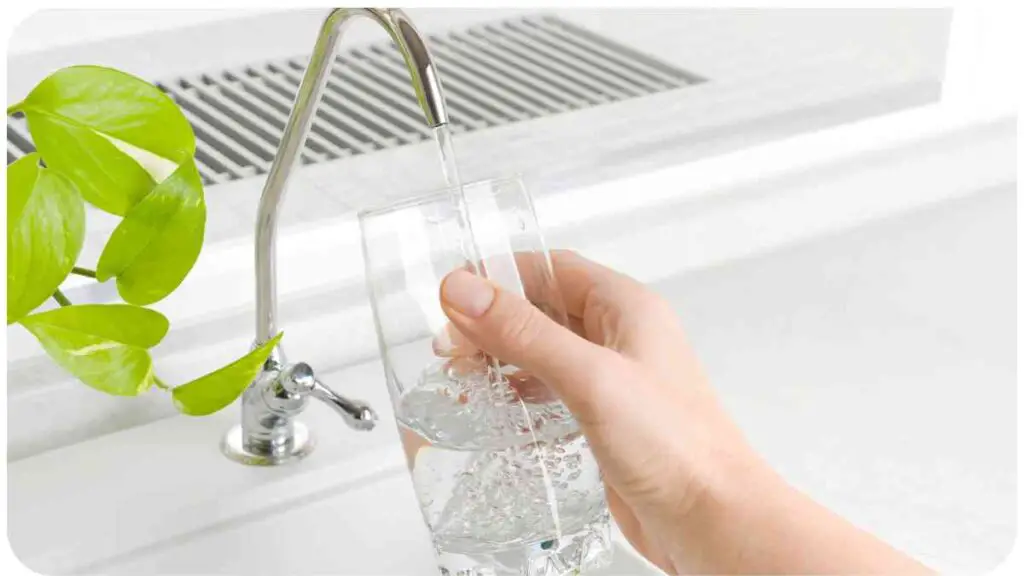 a hand holding a glass of water in front of a sink