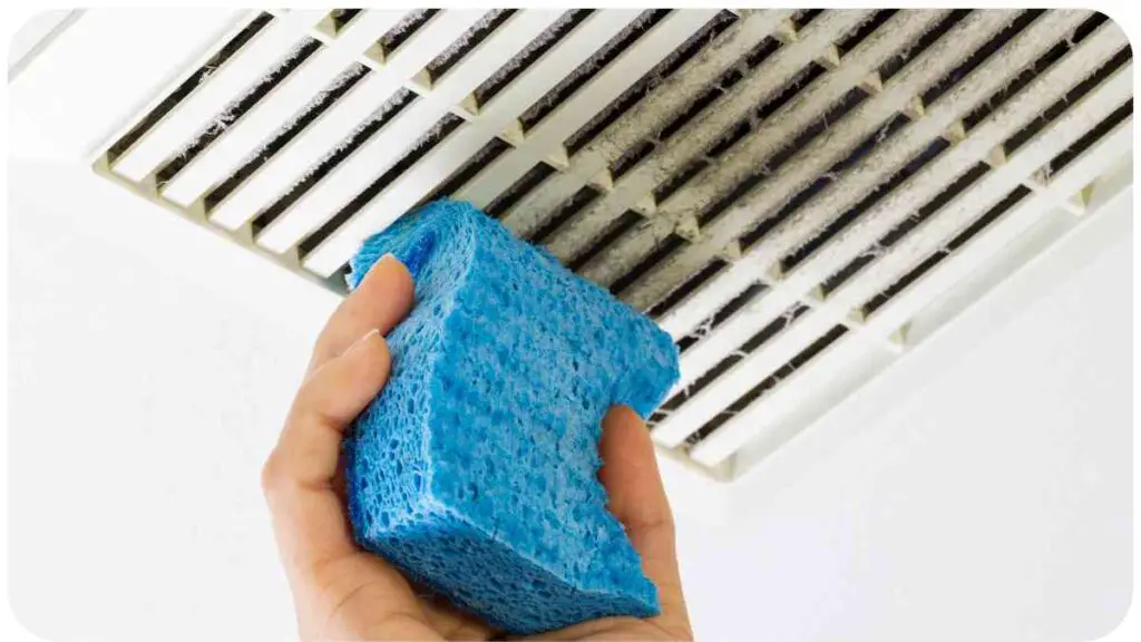 a person is cleaning an air vent with a blue sponge